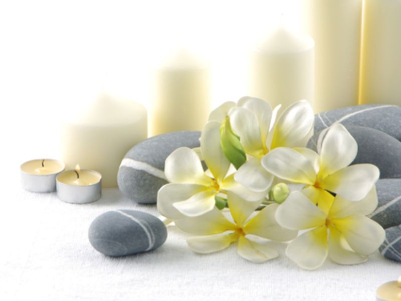 Sarah Butler Therapies - Image of white flowers nestled in front of grey stones with white candles behind